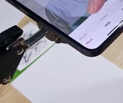 # Da Vinci Eye Drawing Tutorial In this screenshot, a person is using a smartphone to view a reference image of an eye while drawing it on paper using a pencil, demonstrating a common technique for learning to draw realistic eyes by following along with the tutorial.