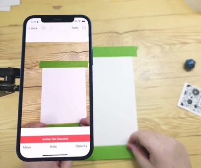 # Screenshot Description The user is demonstrating a digital design tool on their iPhone that displays an augmented reality overlay of green rectangular shapes and white spaces on a wooden surface, with an "Anchor Not Detected" message visible at the bottom of the screen.