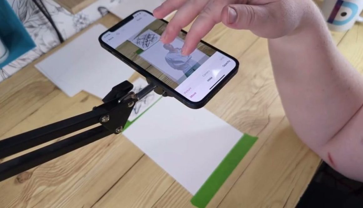 # Image Description A person is using the Da Vinci Eye app on their smartphone to trace or capture a reference image of a paintbrush, demonstrating how the digital tool helps artists study and replicate artistic subjects by photographing them through the app interface.
