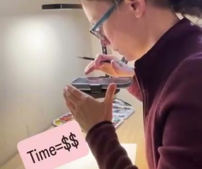 # Description The artist is painting a detailed watercolor portrait of a face while wearing magnifying glasses, with a timer showing "Time=$$$" displayed on a pink note, indicating this is a paid tutorial or demonstration.