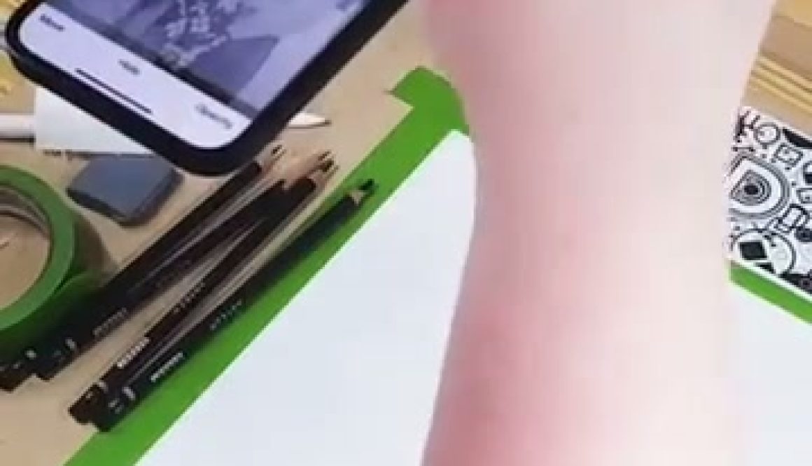 A person is drawing or tracing an image displayed on a smartphone onto paper using the Da Vinci Eye technique, which projects the phone's image to help with accurate sketching.
