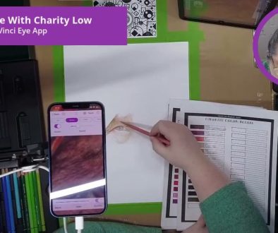# Screenshot Description In this Da Vinci Eye App tutorial, the person is demonstrating how to use the app to match and blend colors while drawing, as shown by the smartphone displaying a color palette alongside a physical color reference chart they're consulting during their live drawing session.